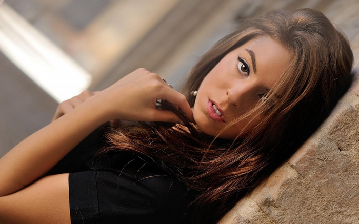 Woman leaning against a textured wall