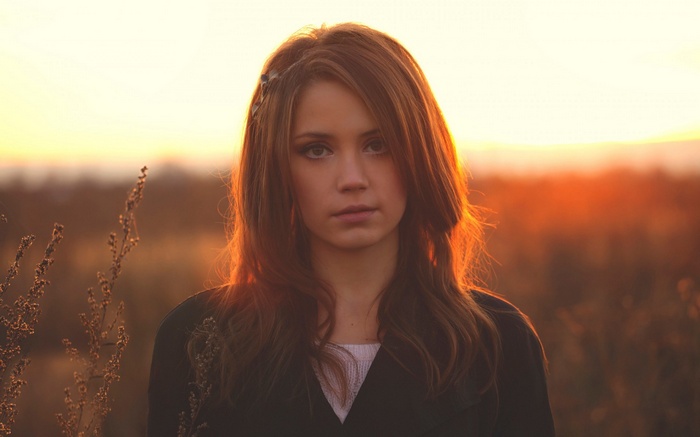 Young woman in field at sunset