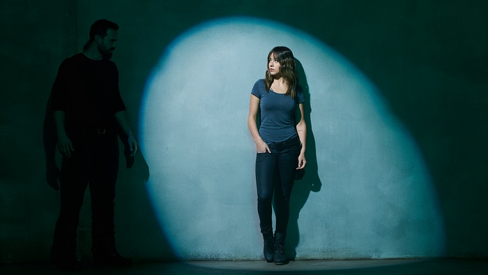 Chloe Bennet in a dark room with spotlight