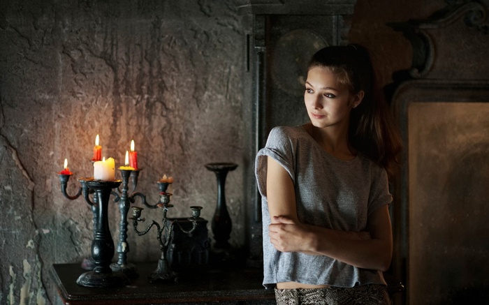 Young woman by candelabra in dark room