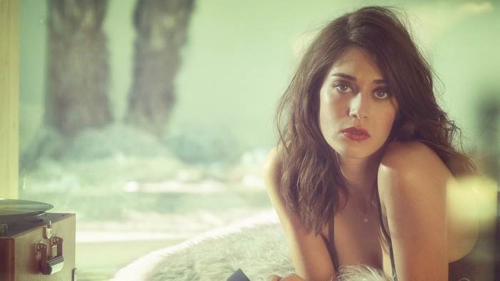 Lizzy Caplan posing by a window