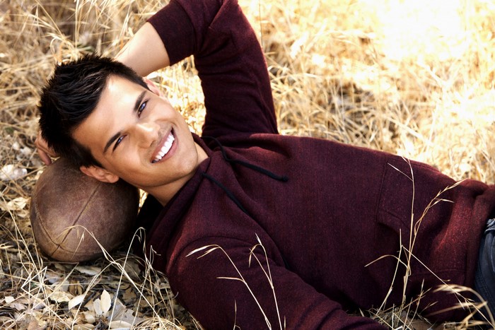 Taylor Lautner lying down with a football