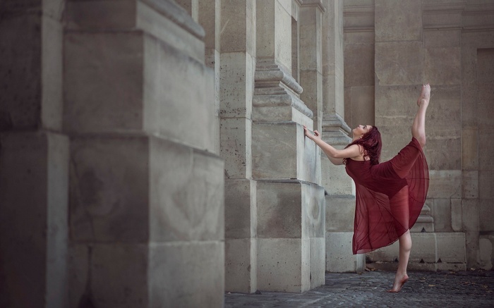 Ballerina performing a split near stone columns