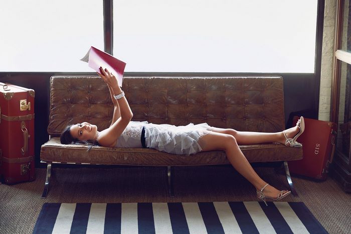 Olivia Munn reading a book on a couch