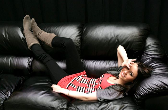 Miley Cyrus lying on a black leather couch