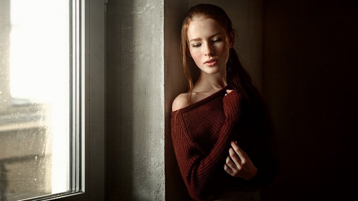Young woman with red hair by a window