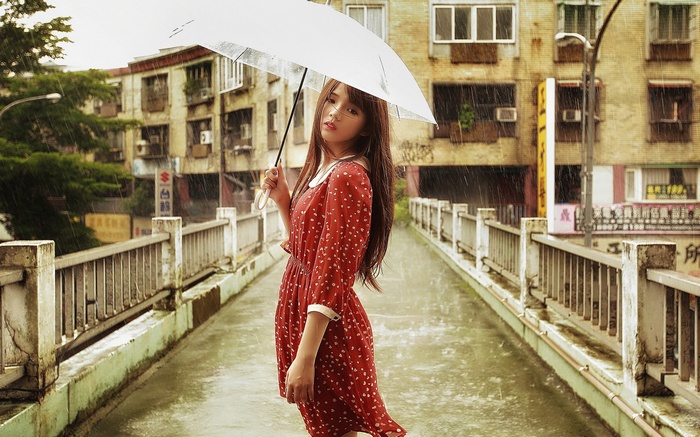 Girl with umbrella in the rain on a bridge