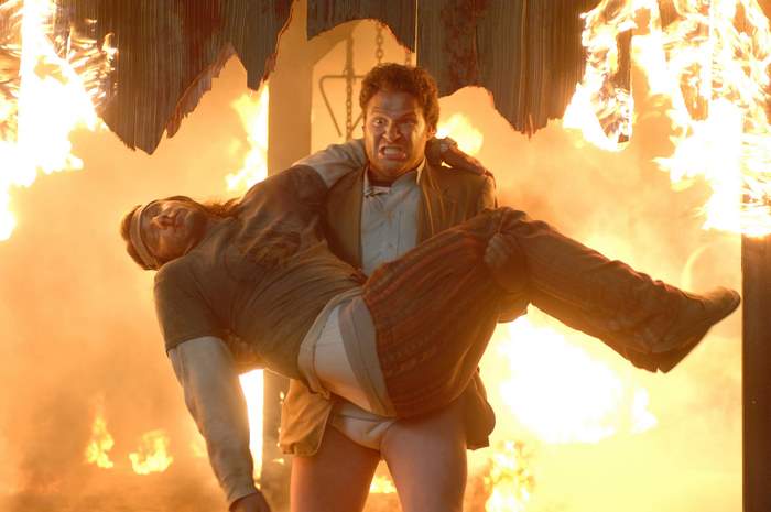 Seth Rogen carrying a man through fire