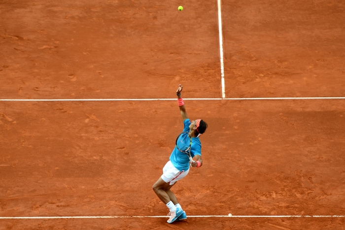Rafael Nadal serving on a clay tennis court