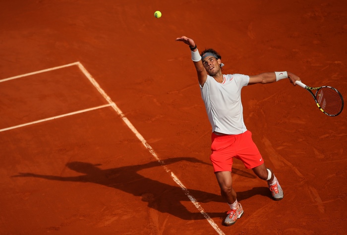 Rafael Nadal serving on a clay tennis court