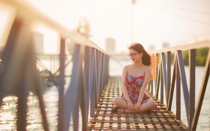 Woman in red dress sitting on a bridge