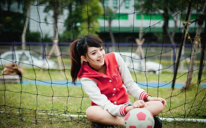 Girl in red jacket with soccer ball