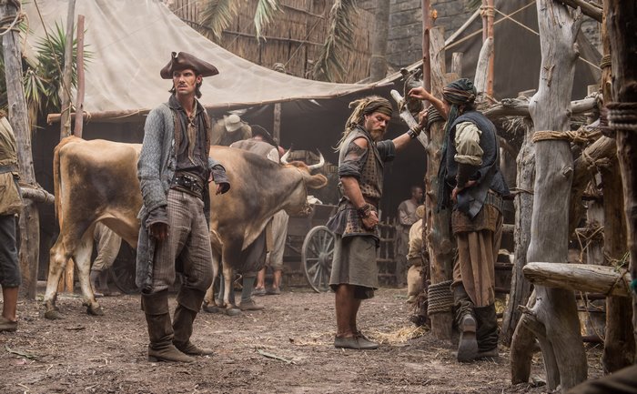 Toby Schmitz as a pirate in a market with cattle