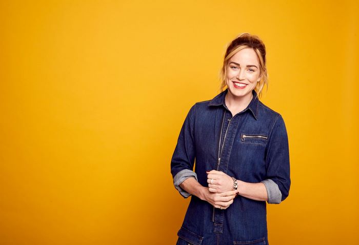 Caity Lotz smiling in a denim jumpsuit