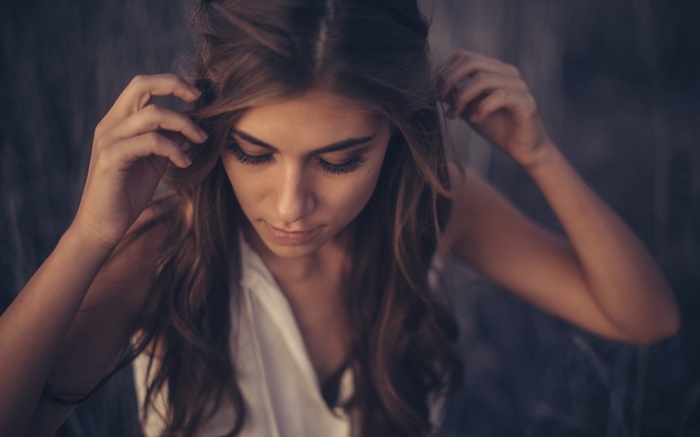 Woman with long wavy hair touching her head