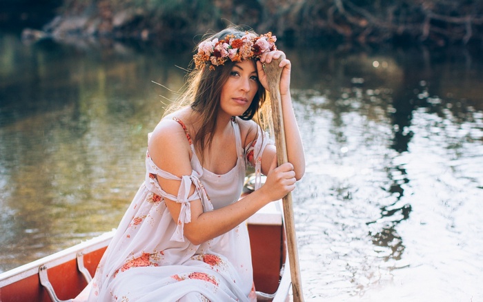 Woman in floral dress in a canoe with a paddle