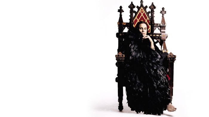 Woman in black feather dress sitting on a throne