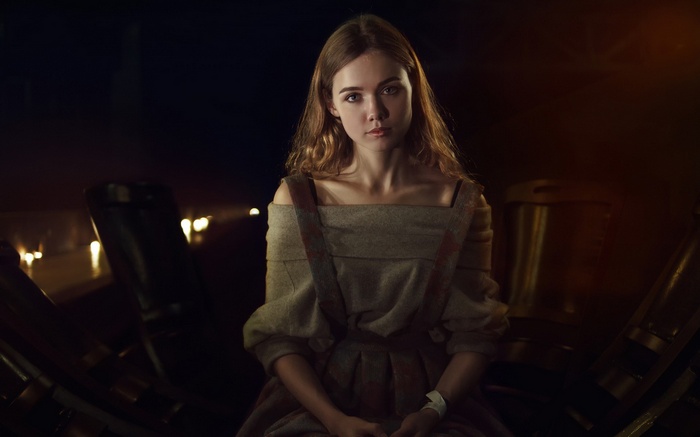 Young woman in historical dress sitting in dim light