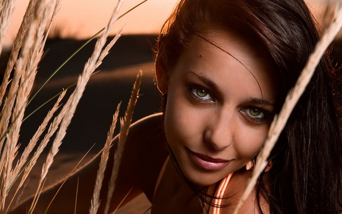 Woman with green eyes behind tall grass