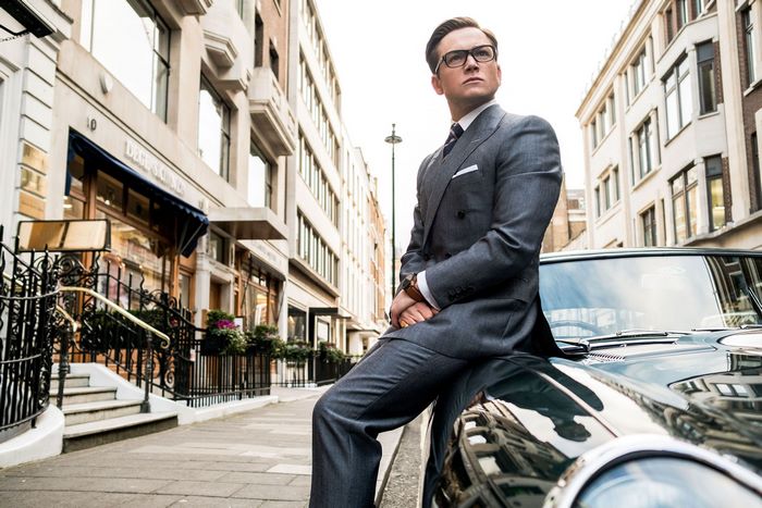 Taron Egerton in a Suit Sitting on a Car