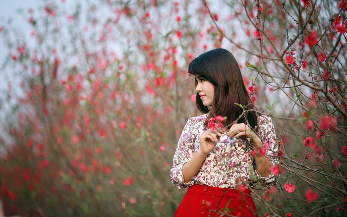 Woman in floral shirt and red skirt among pink flowers
