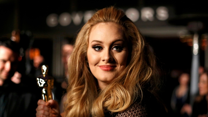 Adele holding an Oscar award