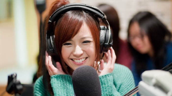 Woman wearing headphones and speaking into a microphone