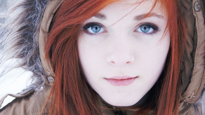 Close-up of a young woman with red hair and blue eyes