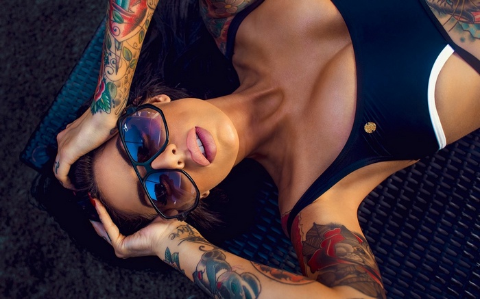Woman with tattoos wearing sunglasses and swimsuit