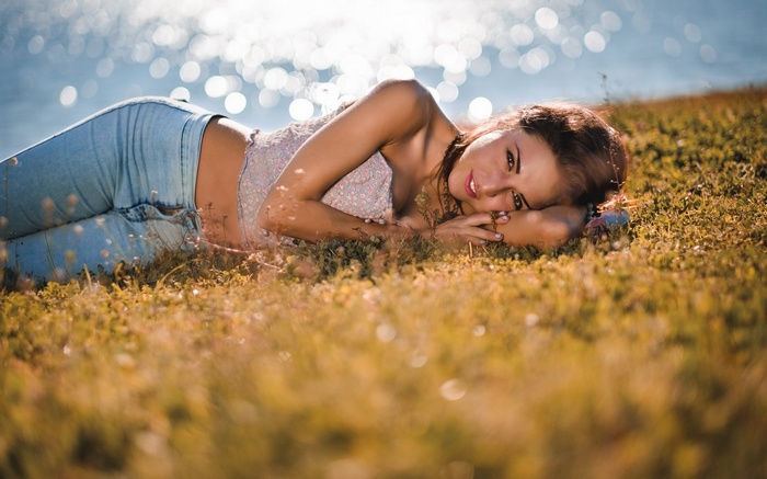 Woman lying on grass near water