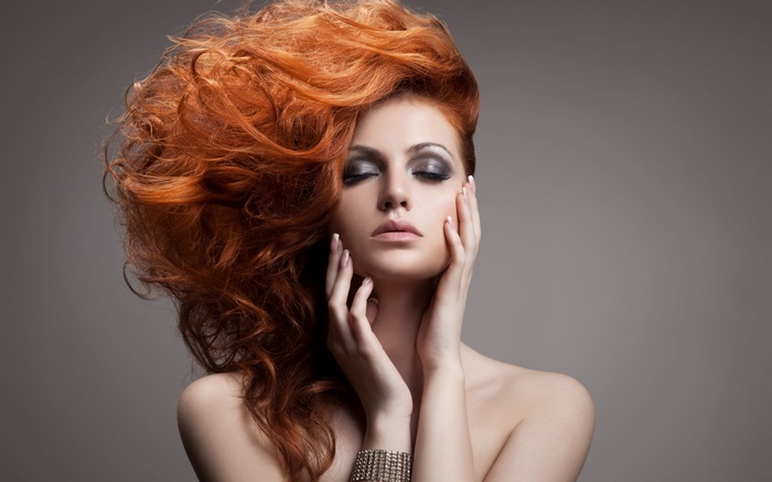 Woman with voluminous red hair and dramatic makeup
