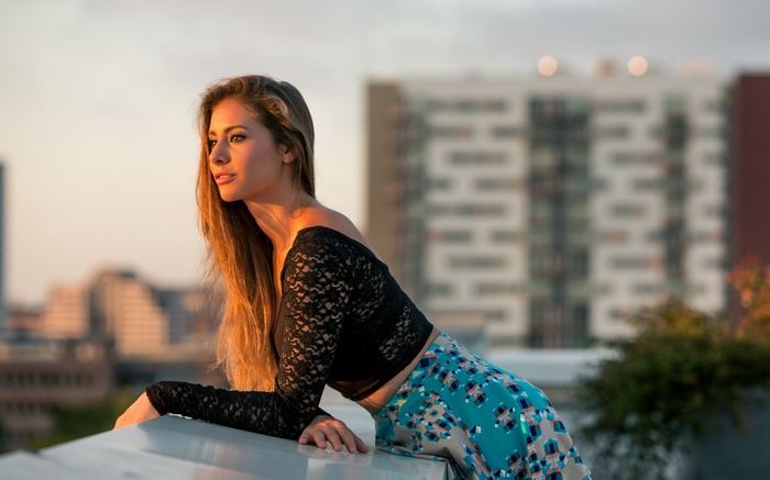 Woman in black lace top and patterned skirt on rooftop