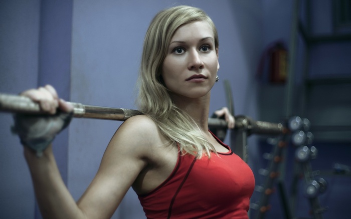 Woman in red tank top holding a barbell