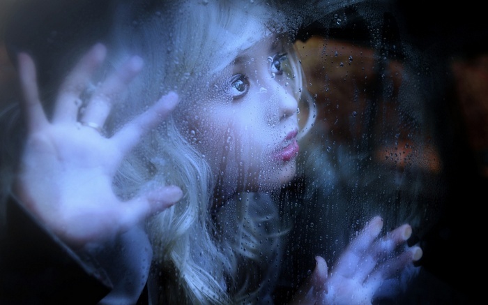 Woman looking through a rainy window