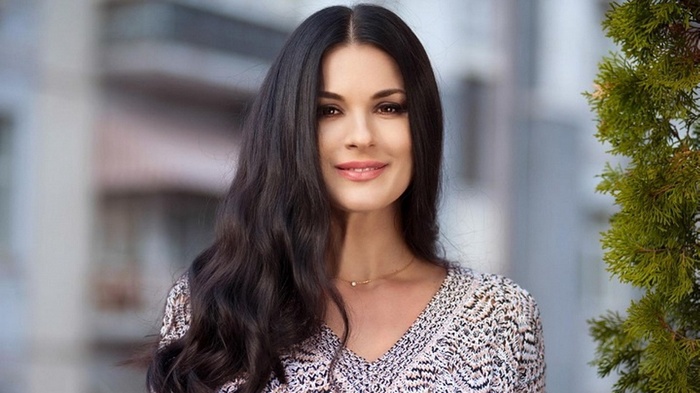 Woman with long dark hair wearing a patterned top