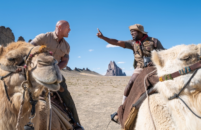 Kevin Hart and Dwayne Johnson riding camels in desert