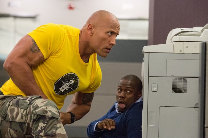 Dwayne Johnson and Kevin Hart hiding behind a copier