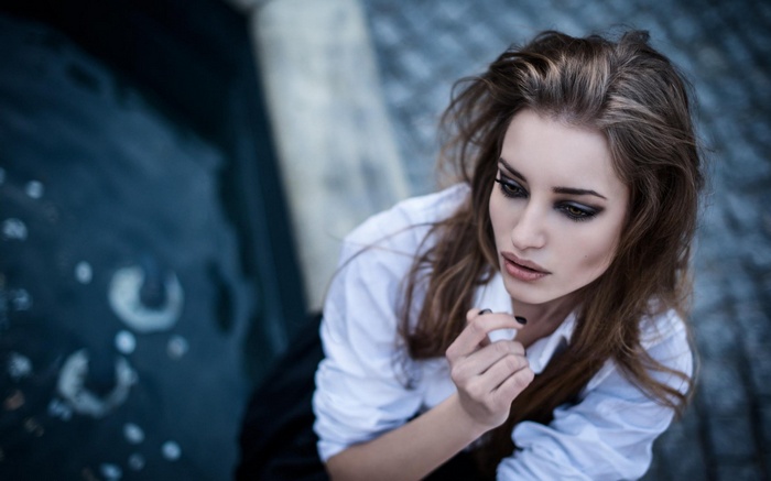 Woman with dark eye makeup and white shirt