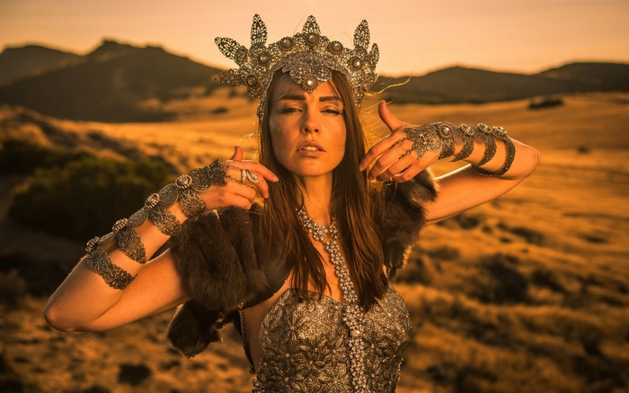 Woman in ornate crown and armor in a desert landscape