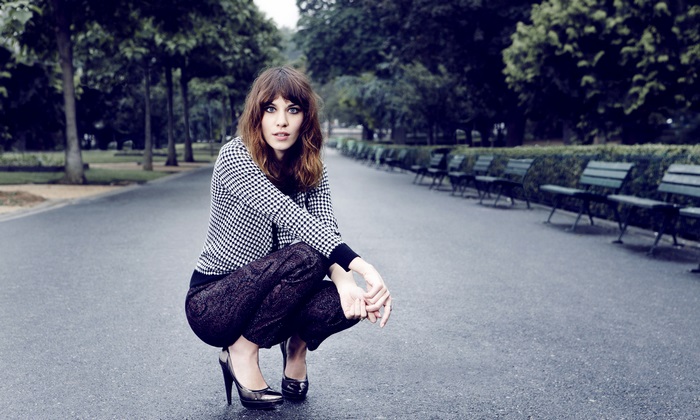 Alexa Chung crouching in a park