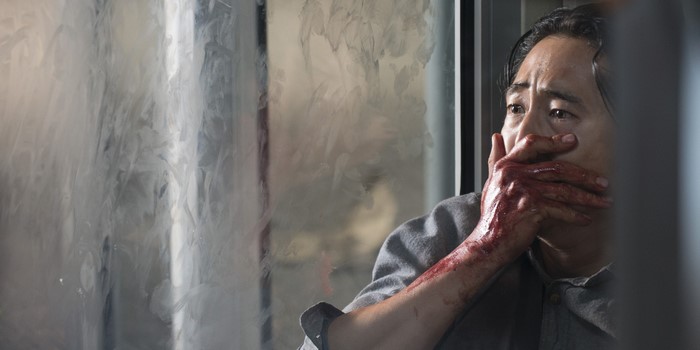 Steven Yeun with bloody hand over mouth