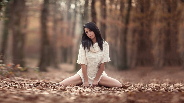 Woman in sweater sitting in autumn forest