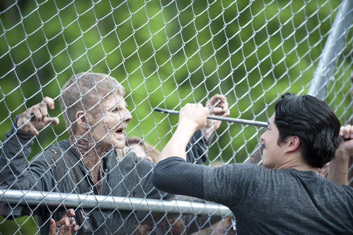 The Walking Dead: Glenn Rhee and a Walker behind a fence