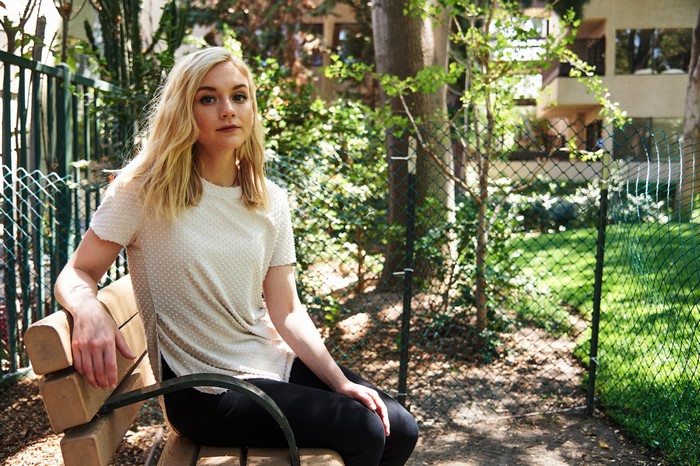 Emily Kinney sitting on a bench outdoors