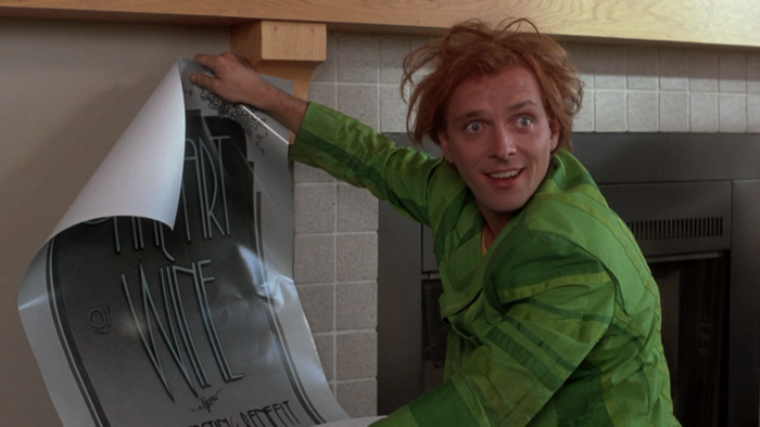 Rik Mayall hanging a poster