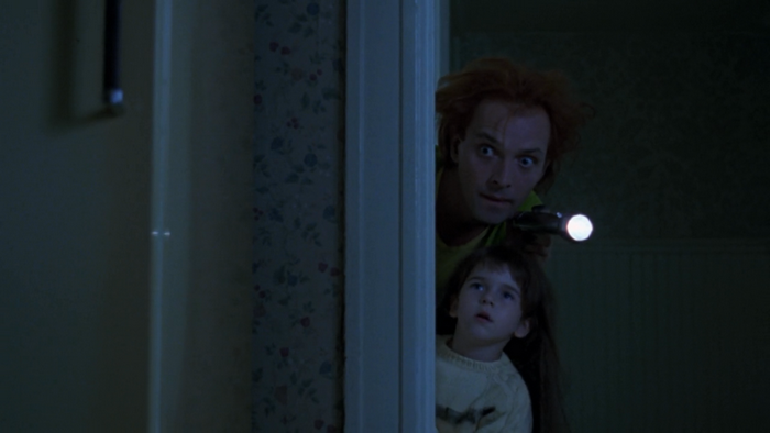 Rik Mayall and a child peeking around a door