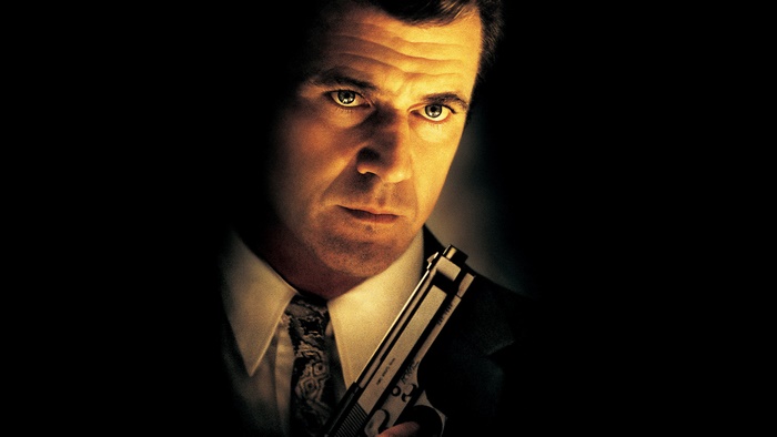 Mel Gibson in a suit holding a gun