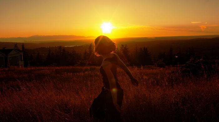 Woman dancing in a field at sunset