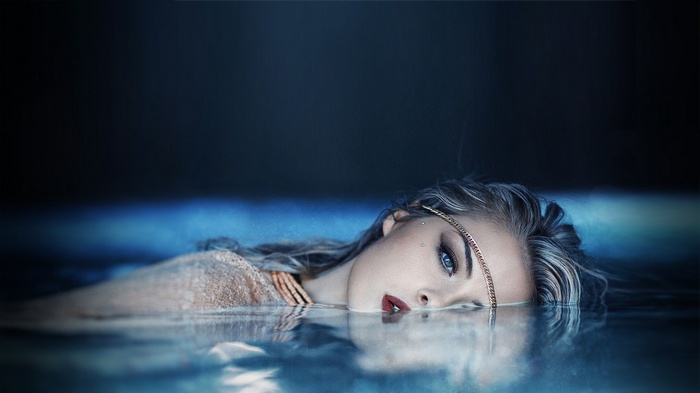 Woman submerged in water with jewelry