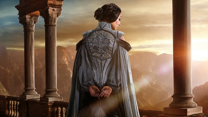Woman in ornate dress on balcony overlooking mountains